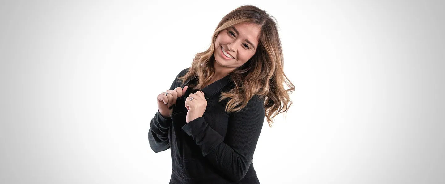 Team portrait: a woman laughing, hugging herself.